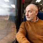 senior man gazing out a train window