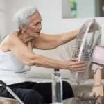 Elderly woman using a fan to stay cool in the summer heat