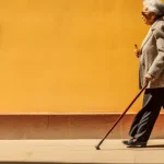 Tip For Seniors: Which Side Do You Use A Cane On? An elderly lady walks along a sidewalk, using a cane.