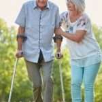 Supporting Seniors: Caring for a Spouse with Parkinson’s woman helping a man who is using canes to walk