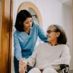 Older Adults: Opting Between Memory & Assisted Living caregiver talking with woman in wheelchair in an assisted living facility